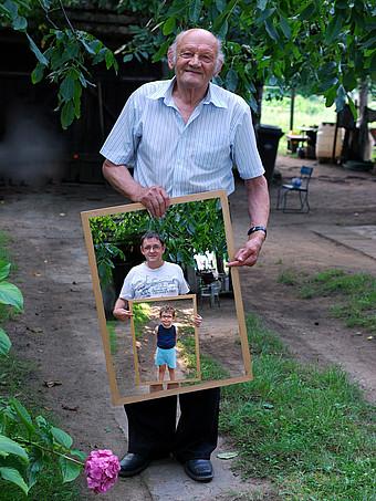 alter Mann mit Foto seiner Nachkommen in den Händen
